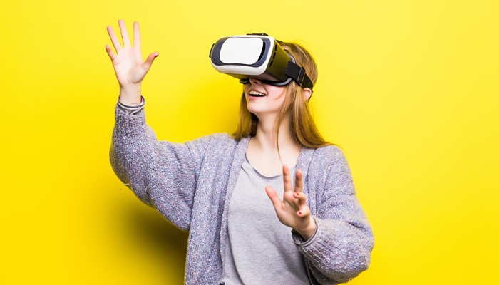 Teenage girl with virtual reality headset on yellow background