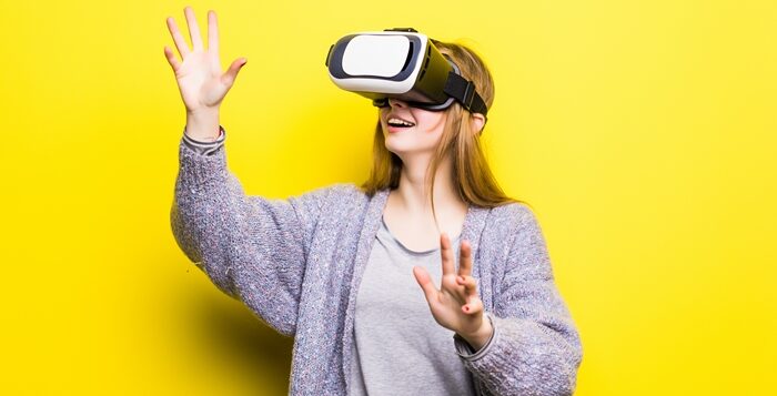 Teenage girl with virtual reality headset on yellow background